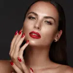 a stunning woman with red fingernails and a really intense red lipstick