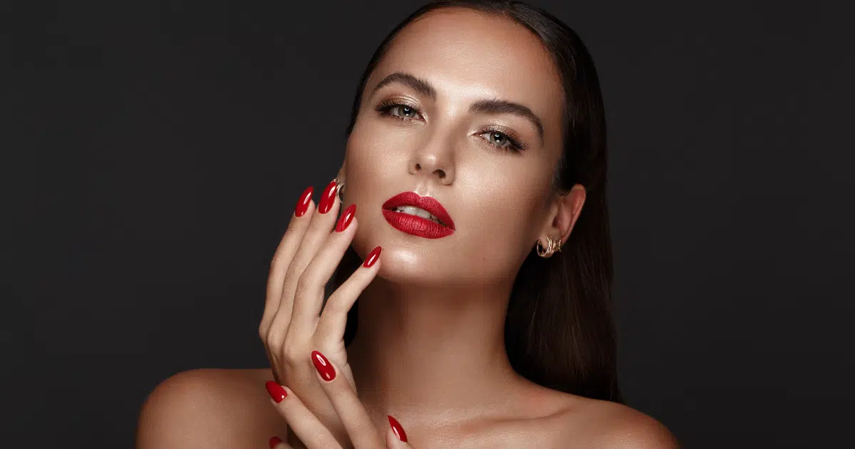 a stunning woman with red fingernails and a really intense red lipstick