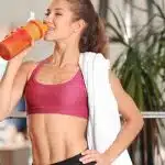 a lovely woman with abs in a pink suit, drinking water