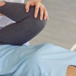 A physical therapist assisting a woman with a leg stretch exercise while she lies on her back